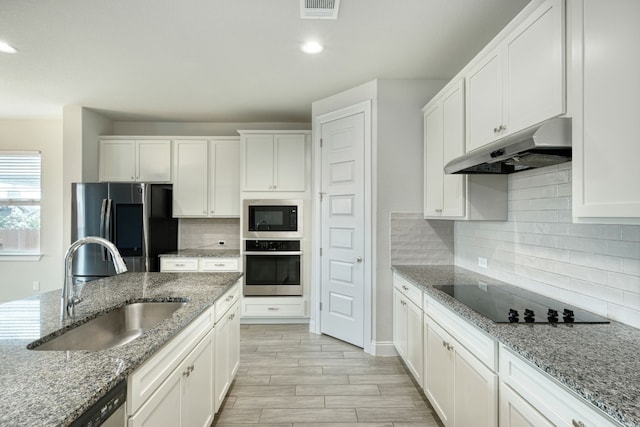 kitchen with light stone counters, white cabinetry, sink, and appliances with stainless steel finishes