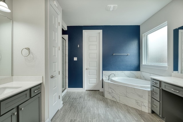 bathroom with hardwood / wood-style flooring, vanity, and plus walk in shower