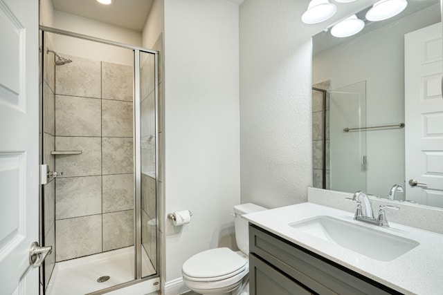 bathroom with vanity, a shower with shower door, and toilet