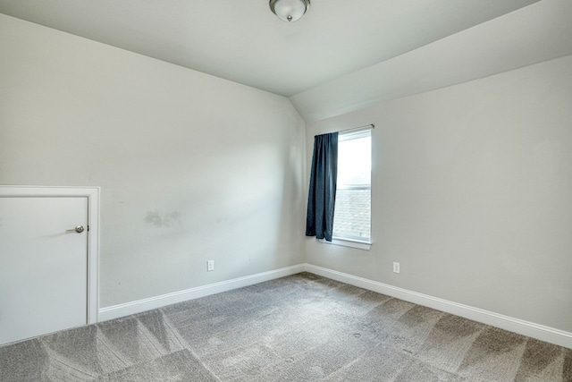 carpeted empty room with lofted ceiling