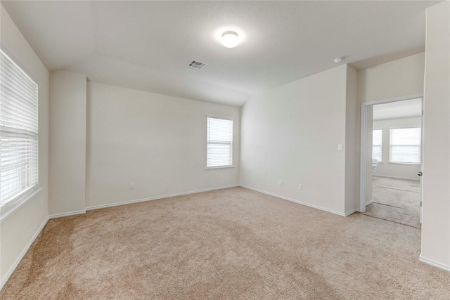 unfurnished room featuring a wealth of natural light, light carpet, and lofted ceiling