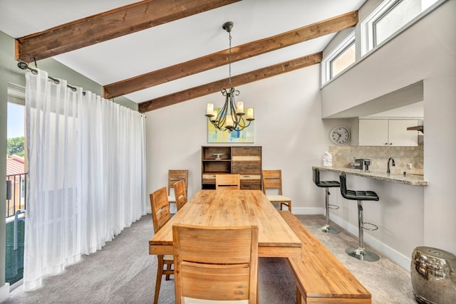 carpeted dining room with beam ceiling, high vaulted ceiling, sink, and an inviting chandelier