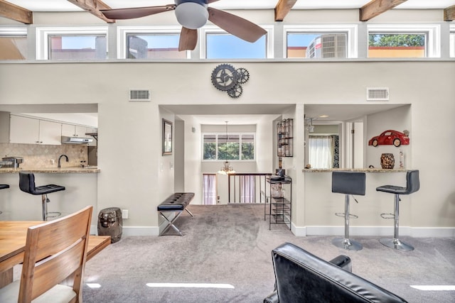 living room featuring a wealth of natural light, beam ceiling, ceiling fan, and carpet floors