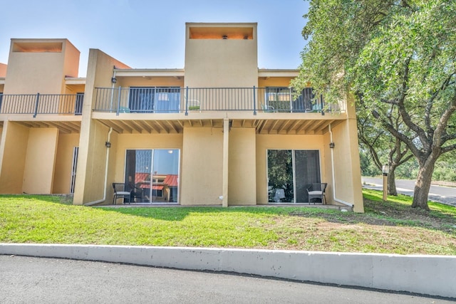 rear view of house featuring a balcony and a yard