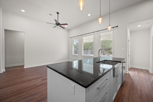 kitchen with dark wood finished floors, a sink, a kitchen island with sink, recessed lighting, and baseboards