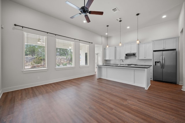 kitchen featuring stainless steel appliances, dark countertops, decorative backsplash, ceiling fan, and dark wood-type flooring
