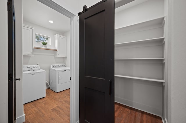 laundry room with cabinets, a barn door, dark hardwood / wood-style floors, and washing machine and clothes dryer