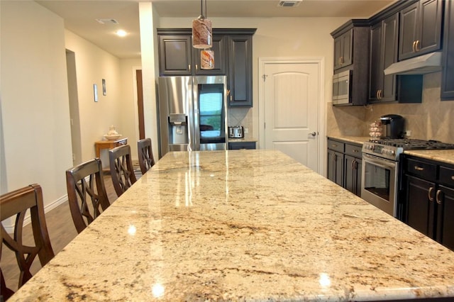 kitchen with decorative backsplash, light stone counters, and appliances with stainless steel finishes