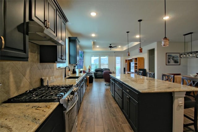 kitchen with pendant lighting, a breakfast bar, a center island, high end range, and sink