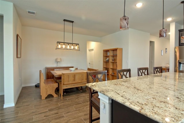 kitchen with stainless steel fridge, light stone counters, and hanging light fixtures