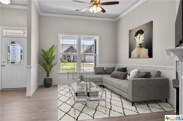 living room with ornamental molding, ceiling fan, and light hardwood / wood-style flooring