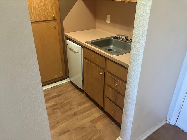 kitchen with white dishwasher, sink, and light hardwood / wood-style flooring