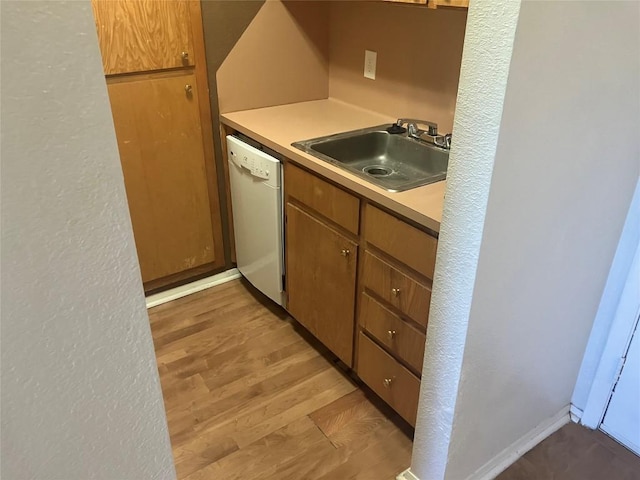 kitchen featuring light wood-style flooring, a sink, light countertops, dishwasher, and brown cabinetry