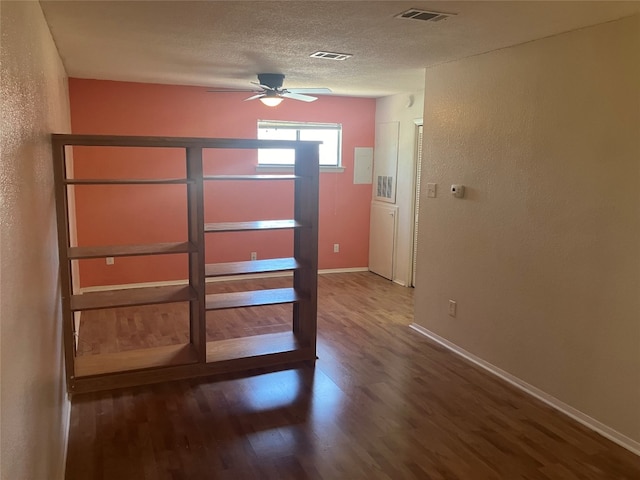 interior space featuring a textured ceiling, wood finished floors, visible vents, and baseboards