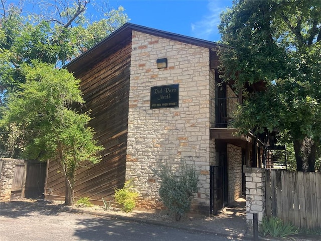 view of property exterior with stone siding and fence