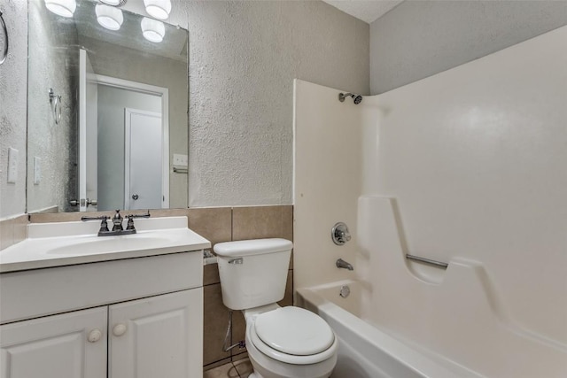 full bathroom featuring shower / washtub combination, tile walls, vanity, and toilet