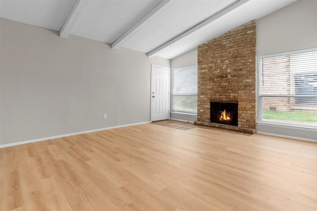 unfurnished living room with a fireplace, lofted ceiling with beams, light hardwood / wood-style floors, and a textured ceiling