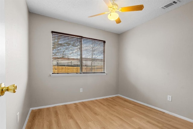 spare room with ceiling fan, a textured ceiling, and light wood-type flooring