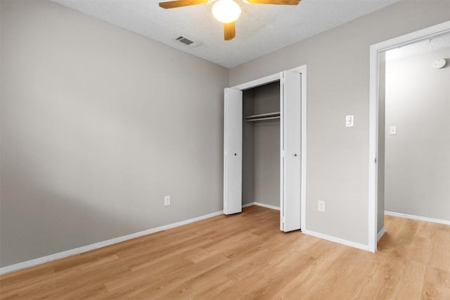 unfurnished bedroom with ceiling fan, a closet, a textured ceiling, and light wood-type flooring