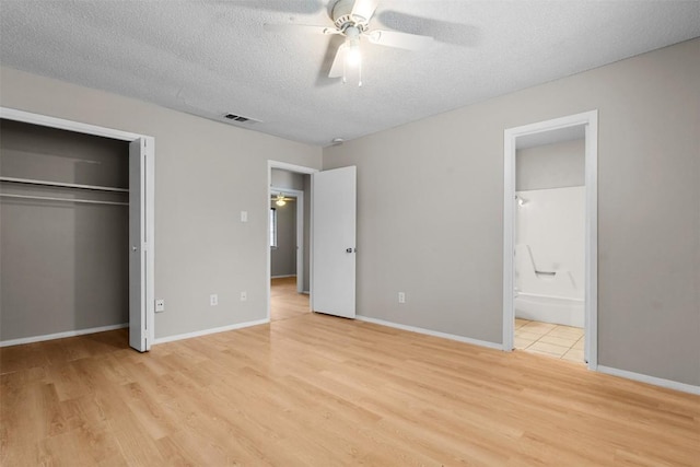 unfurnished bedroom with a closet, a textured ceiling, light wood-type flooring, and ensuite bath