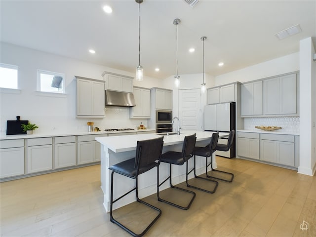 kitchen featuring pendant lighting, stainless steel microwave, white refrigerator, range hood, and gas cooktop