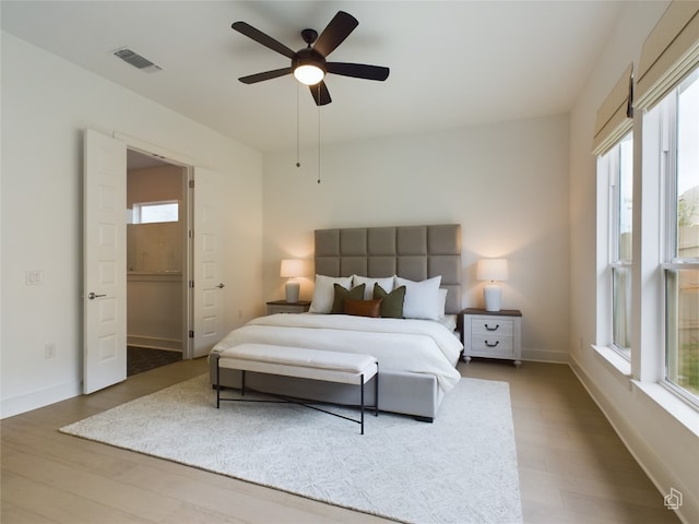 bedroom featuring multiple windows, hardwood / wood-style flooring, and ceiling fan