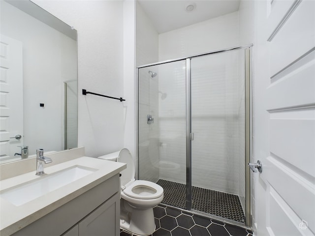 bathroom featuring tile patterned flooring, a shower with door, vanity, and toilet