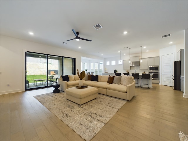 living room with ceiling fan and light hardwood / wood-style floors