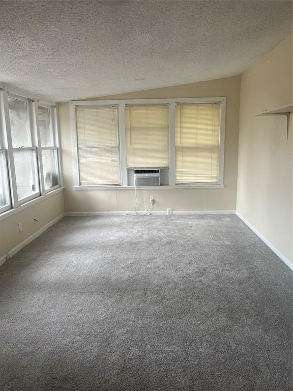 unfurnished living room featuring carpet floors, cooling unit, and a textured ceiling