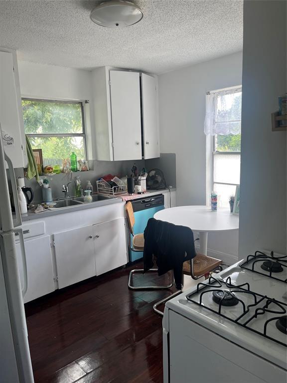 kitchen featuring white cabinets, a textured ceiling, and white appliances