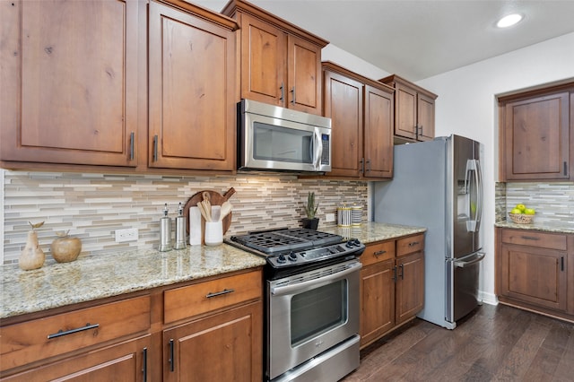 kitchen featuring light stone counters, dark wood-type flooring, stainless steel appliances, and tasteful backsplash