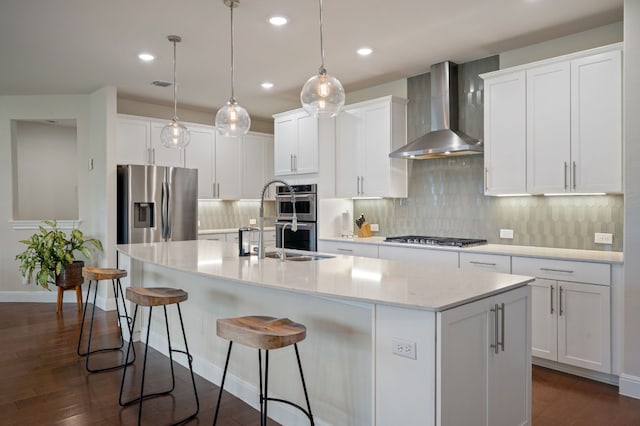 kitchen with wall chimney exhaust hood, pendant lighting, white cabinets, and appliances with stainless steel finishes