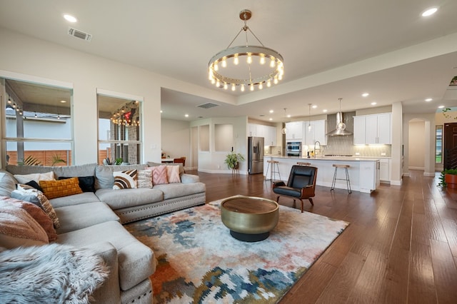 living room featuring dark wood-type flooring, a notable chandelier, and sink