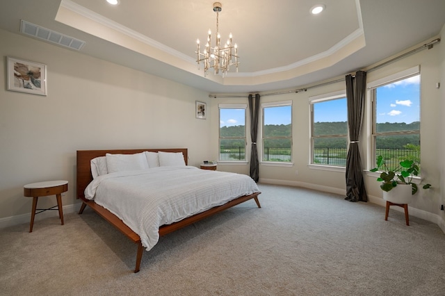 carpeted bedroom featuring crown molding, a tray ceiling, and a notable chandelier