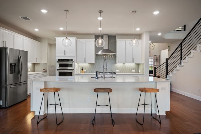 kitchen featuring stainless steel appliances, dark hardwood / wood-style floors, a large island, and wall chimney exhaust hood