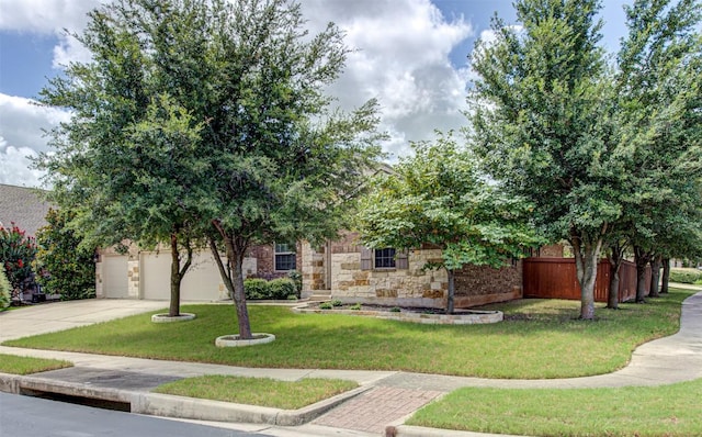 view of property hidden behind natural elements featuring a front lawn and a garage