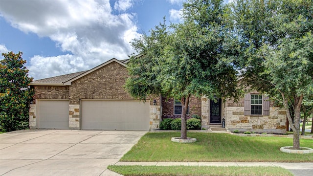 3113 Pasqueflower Pass, Pflugerville, TX 78660 - view of property hidden behind natural elements featuring an attached garage, concrete driveway, a front yard, and stone siding