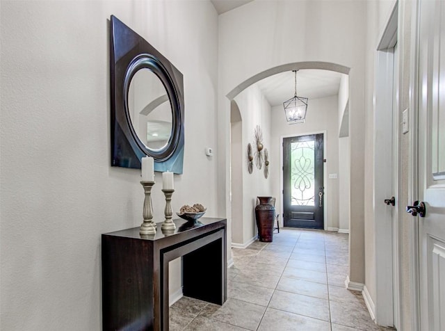 3113 Pasqueflower Pass, Pflugerville, TX 78660 - foyer entrance featuring arched walkways, baseboards, light tile patterned flooring, and a chandelier