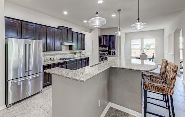 kitchen featuring decorative backsplash, stainless steel appliances, sink, a large island with sink, and pendant lighting