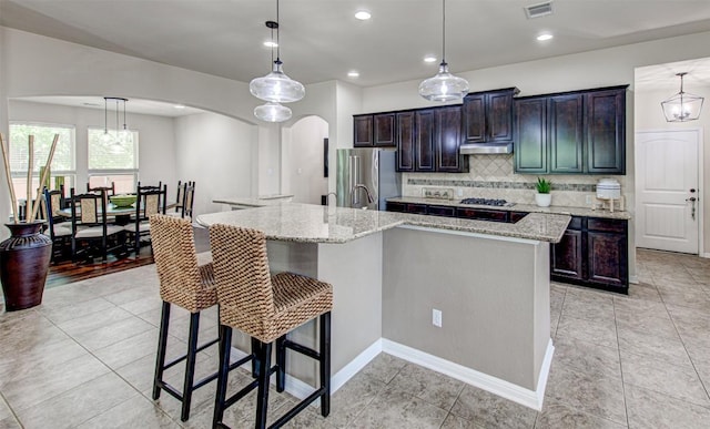 3113 Pasqueflower Pass, Pflugerville, TX 78660 - kitchen with freestanding refrigerator, arched walkways, a large island, tasteful backsplash, and a kitchen bar