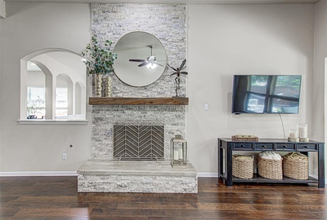 living room with a stone fireplace, ceiling fan, and dark hardwood / wood-style flooring