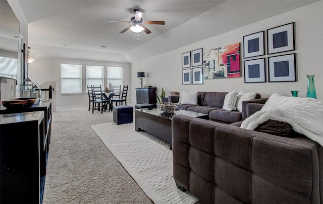 carpeted living room with ceiling fan and vaulted ceiling