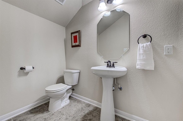 bathroom with toilet and lofted ceiling