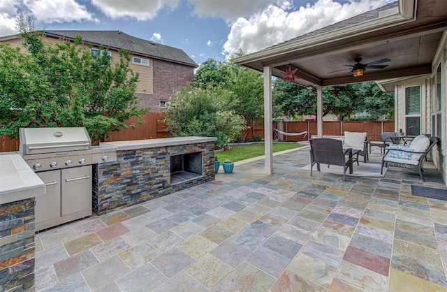 view of patio with an outdoor living space with a fireplace, area for grilling, ceiling fan, and a grill