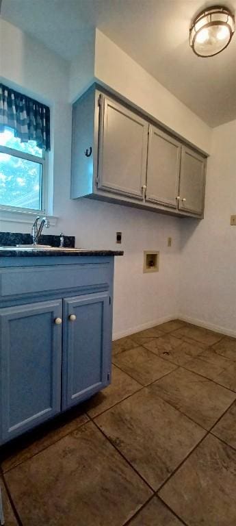 clothes washing area with cabinets, hookup for a washing machine, dark tile patterned floors, and sink