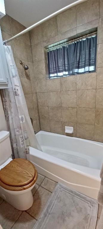 bathroom featuring tile patterned floors, toilet, and shower / tub combo with curtain