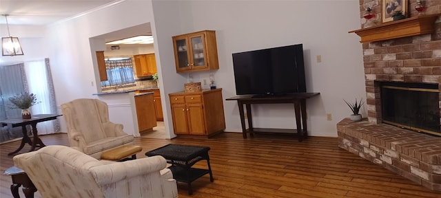 living room featuring a chandelier, light hardwood / wood-style floors, a brick fireplace, and crown molding