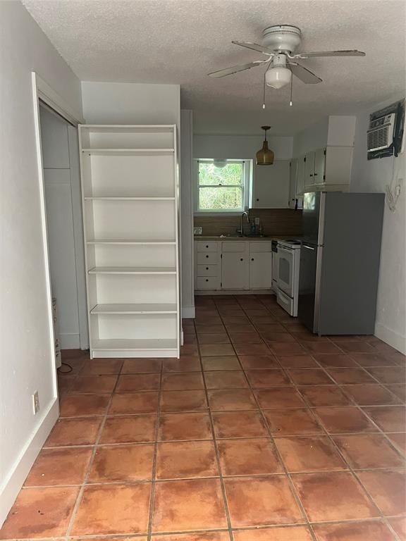 3204 Tom Green St, Austin, TX 78705 - kitchen featuring freestanding refrigerator, white range with electric cooktop, a wall mounted air conditioner, a ceiling fan, and a textured ceiling