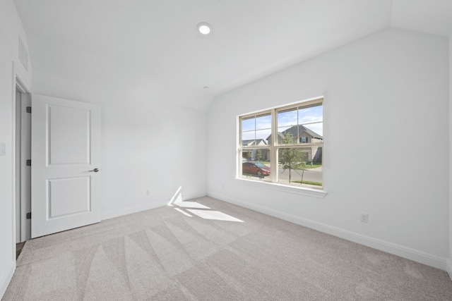 empty room featuring light carpet and vaulted ceiling