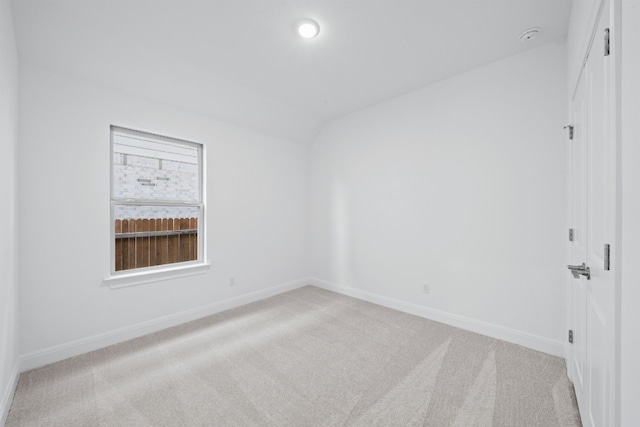 carpeted empty room featuring vaulted ceiling